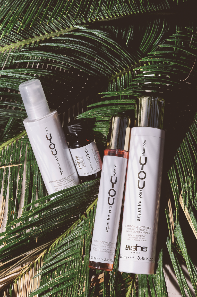 Four she professional hair products laying on plants