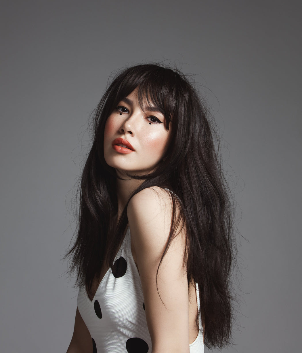 Model with long black/brown hair and tape in extensions.