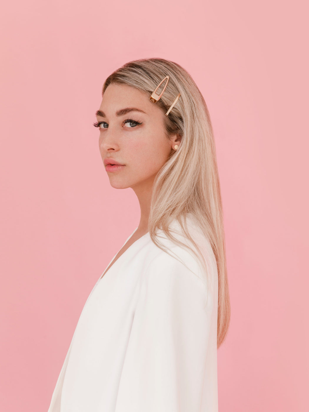 Model wearing rooted hair extensions with pink background.